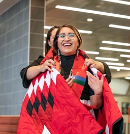 A student being given a blanket during a Native American honors grad ceremony.