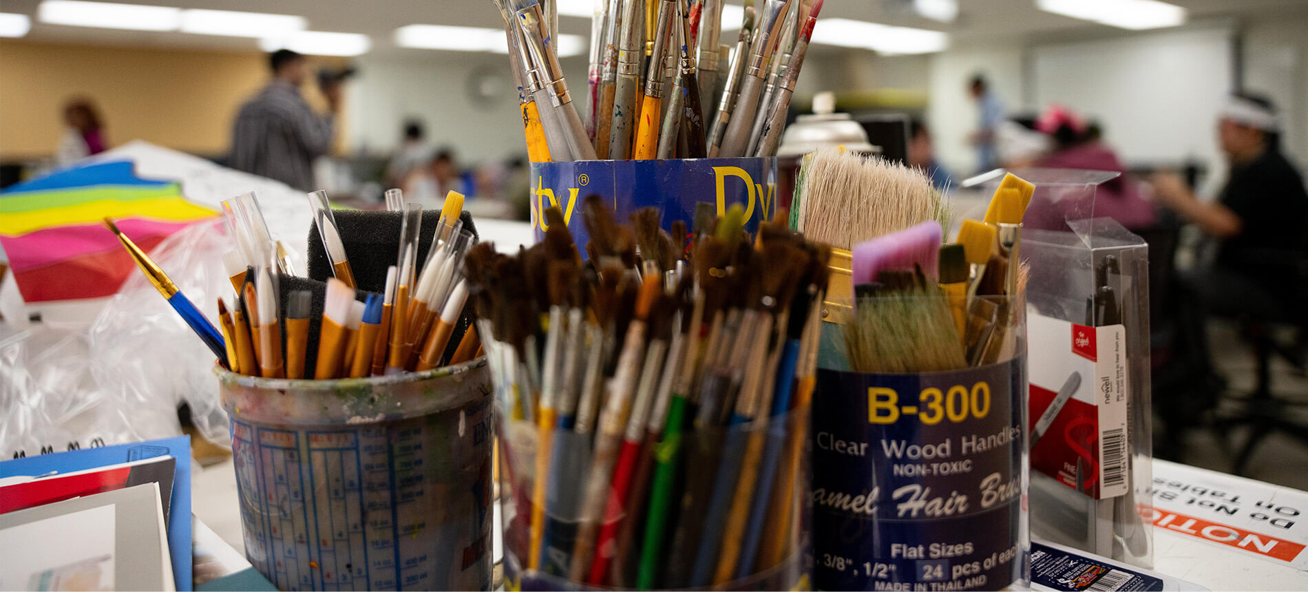 Close up photo of paint brushes on a table in jars
