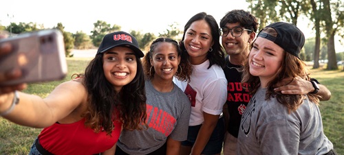 5 students posing for a selfie outside.