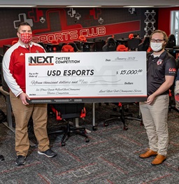 Two USD Esports members holding a large check.