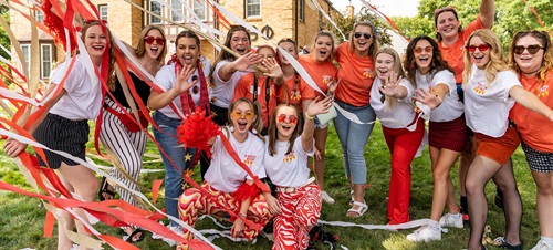 Sorority girls waving at the camera with streamers flying overhead.