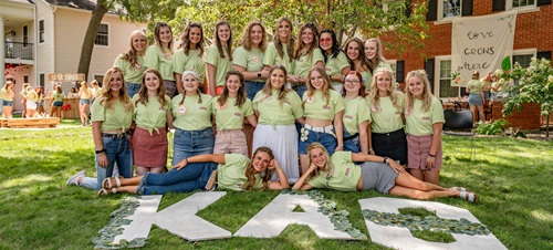 A sorority posing in front of their house.