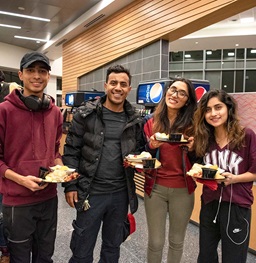 Four students posing with their food in the dining hall.