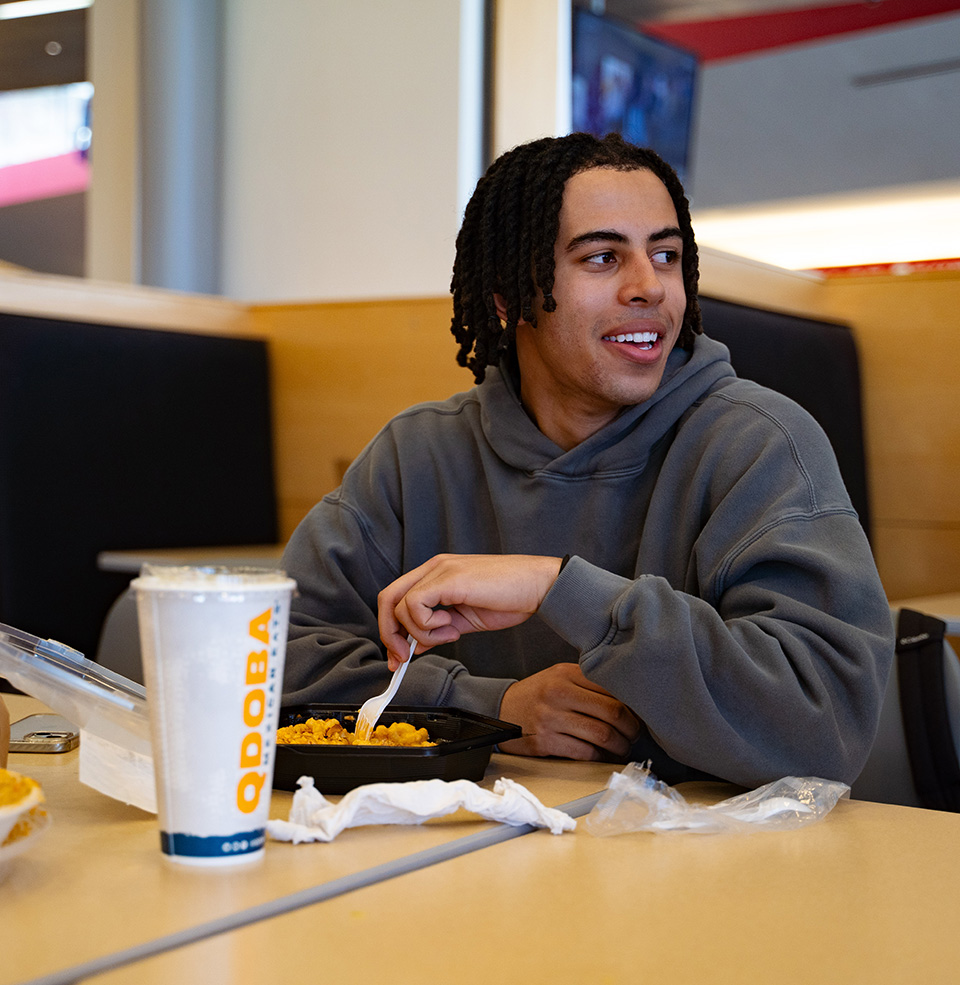 A male student eating Qdoba at a MUC dining table