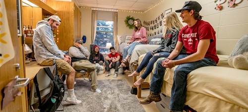 USD students sitting and laughing in a dorm room.