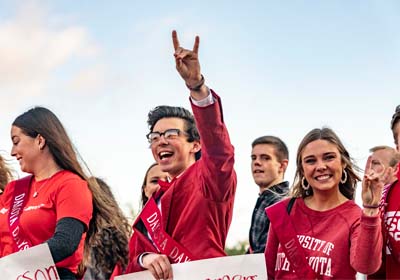 USD Royalty walking with signs while one smiles and holds up a Yote hand sign.