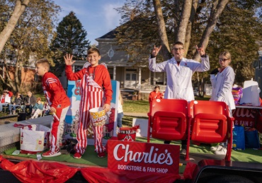 Children smiling and posing in USD clothing on a dakota days parade float.