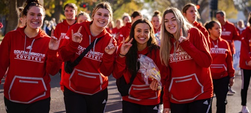 USD students marching in the dakota days parade and smiling.