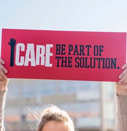 A student holding up an iCare sign that says "Be part of the solution."