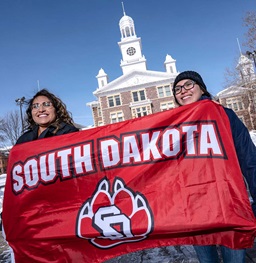 Two native students holding a USD flag.
