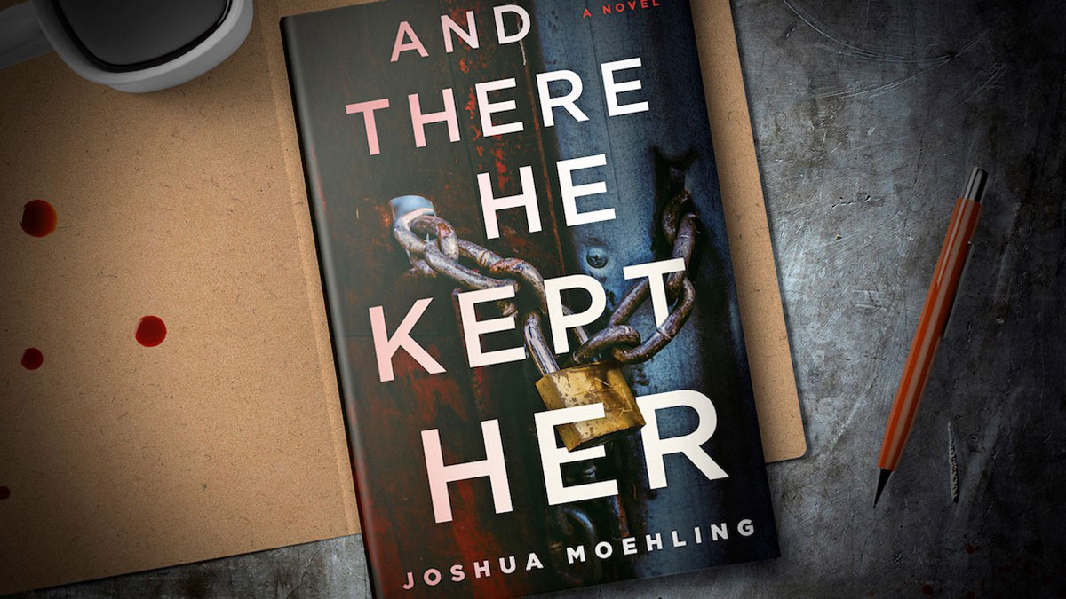 The book And There He Kept Her sits on a table with a pen to the right and drops of red liquid to the left.