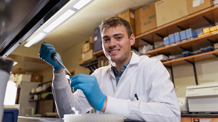 A photo of Mason Woldt sitting and working in a science lab.