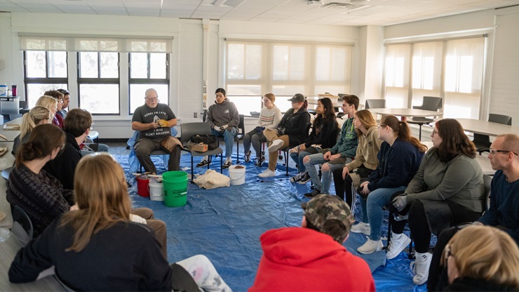 The introduction to archaeology class watches greg haggerty demonstrate flint knapping