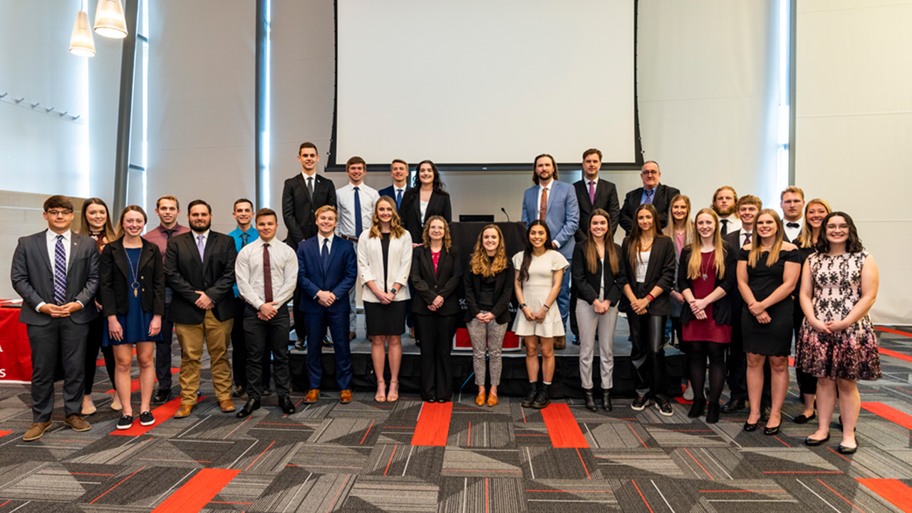 Beta Gamma Sigma inductees stand on stage and pose for a photo.