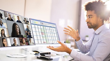 A person is on a Zoom meeting with several colleagues on their computer screen. A person is on a Zoom meeting with several colleagues on their computer screen.