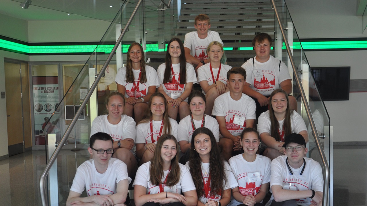 Students sit on the stairs in the Beacom School of Business and pose for a picture.