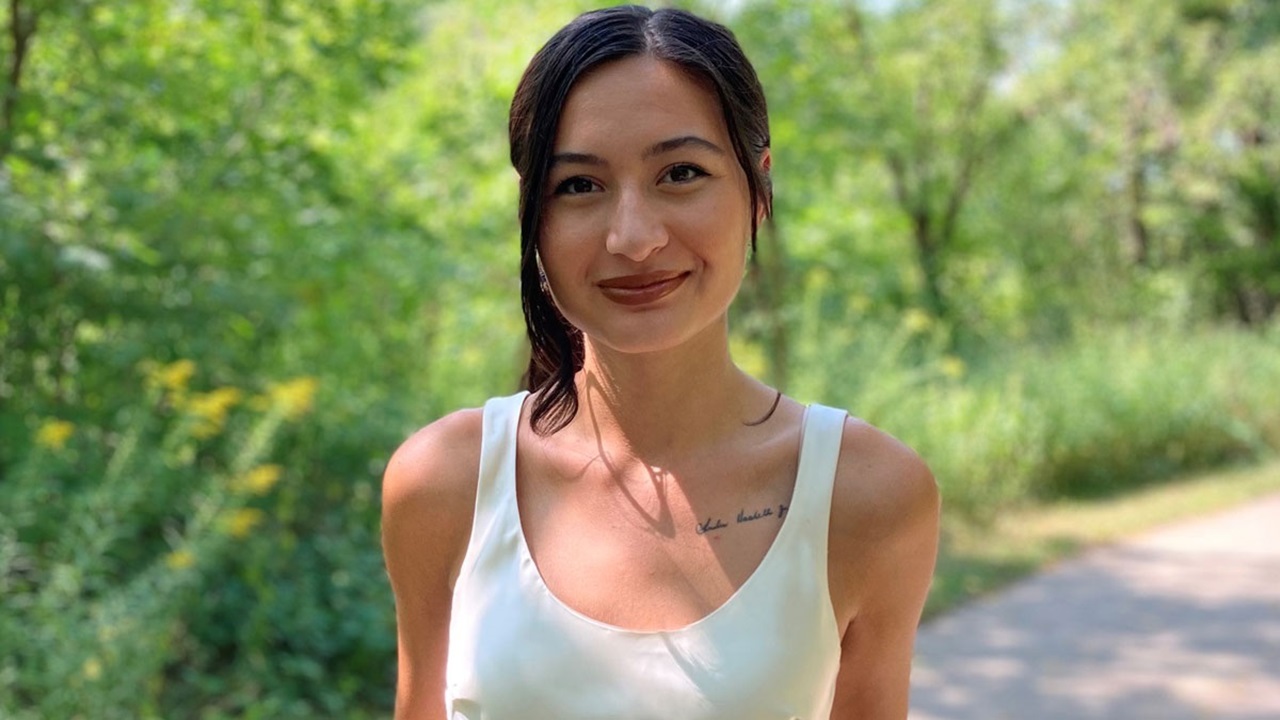 Myah Red Horse smiles for a photo. The background behind her is green trees and plants.