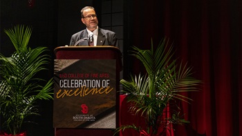 Bruce Kelley speaking behind the podium at the 2021 College of Fine Arts Celebration of Excellence