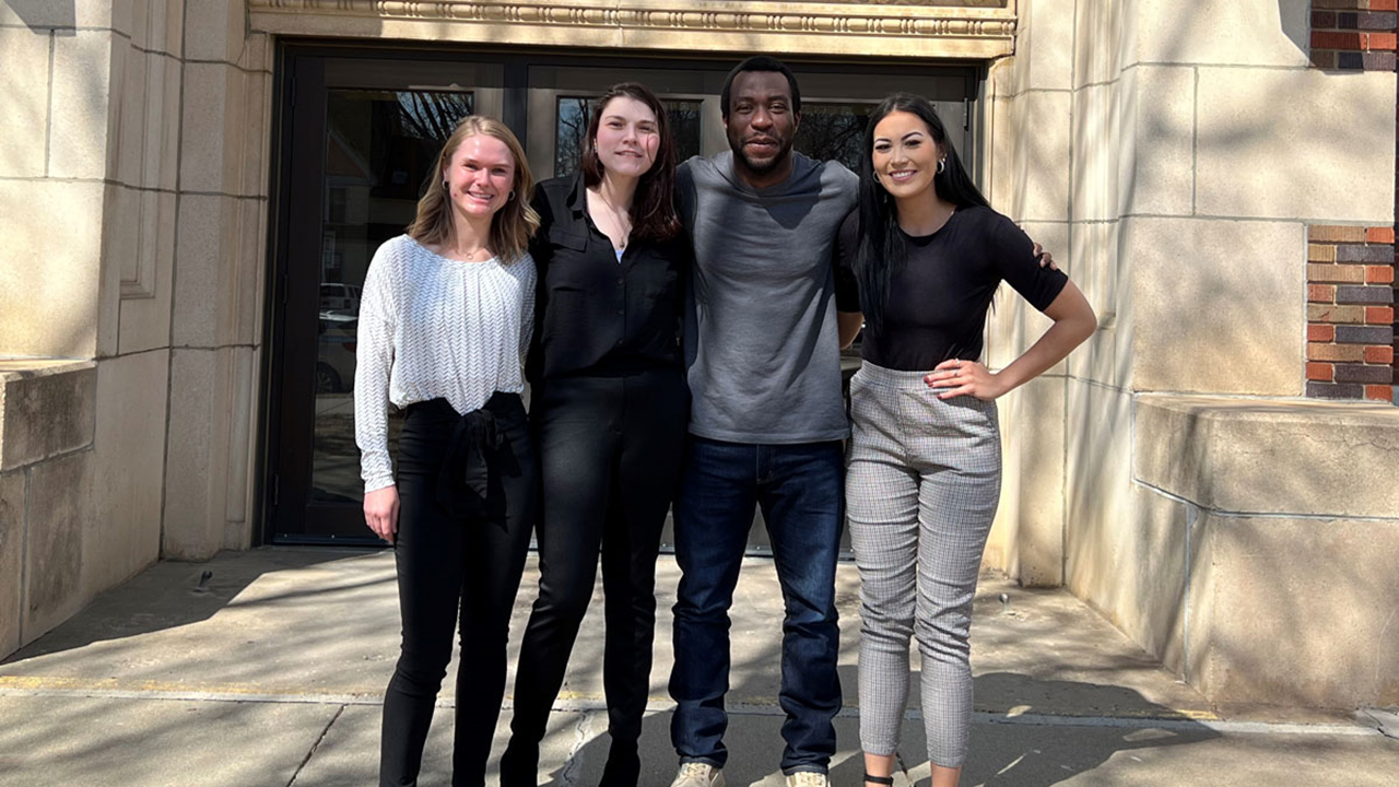 Four psychology graduate students stand next to each other and smile for a photo.
