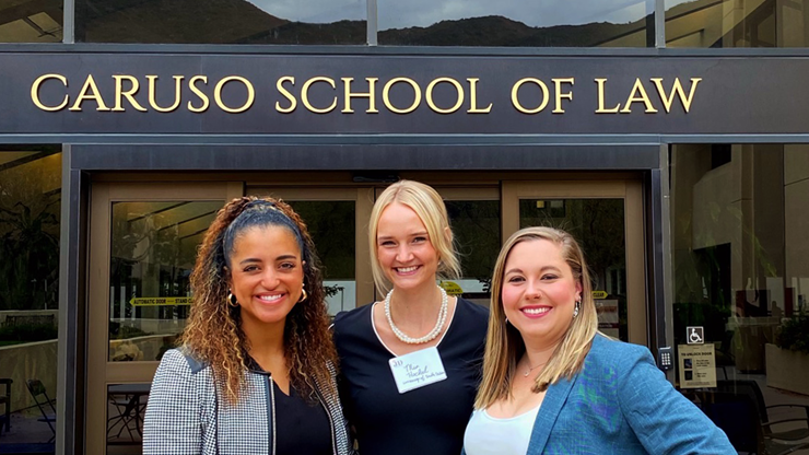 Aliyah Jackson, Mia Hockel and Madelyn Selvaggi stand together for a picture in front of the Caruso School of Law.