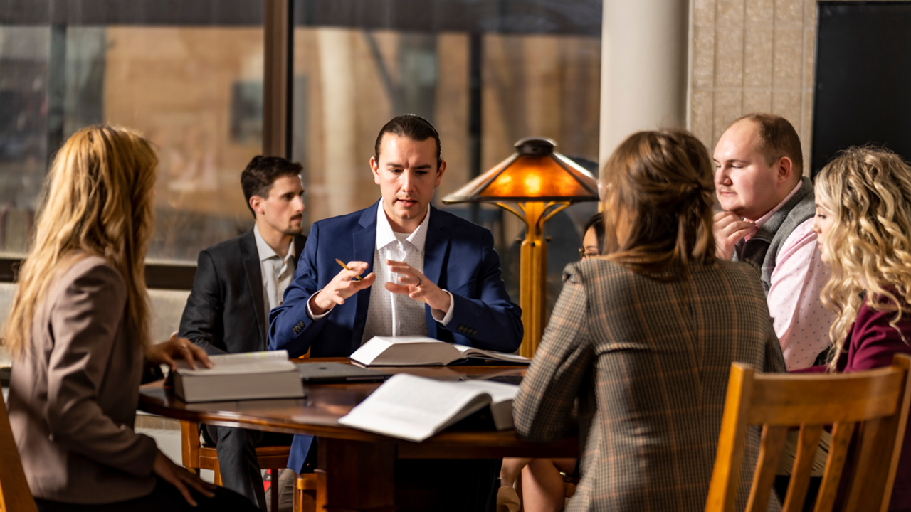 Law students sit around a table and discuss.