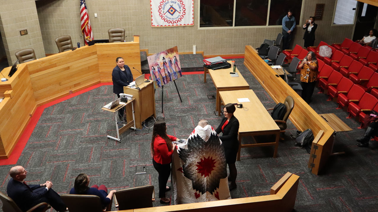 An overhead shot of Judge Sherman Marshall being presented with a star quilt in the courtroom at the University of South Dakota Knudson School of Law.