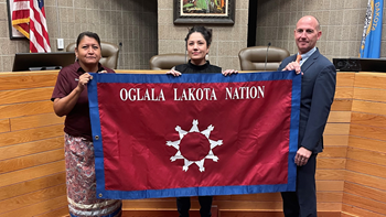 Secretary Stacy Two Lance, law student Maranda Herman and Knudson School of Law Dean Neil Fulton hold a flag from the Oglala Lakota Nation.