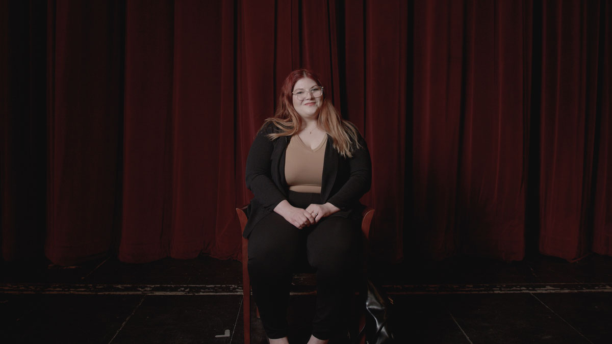 Cassie Thompson sitting on chair in Aalfs Auditorium.