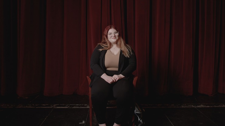 Cassie Thompson sitting on chair in Aalfs Auditorium.