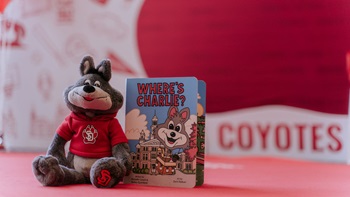 A photo of Where's Charlie next to a miniature plush toy Charlie Coyote
