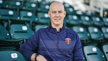 A photo of Corey Wolf sitting in a row of stadium chairs. 