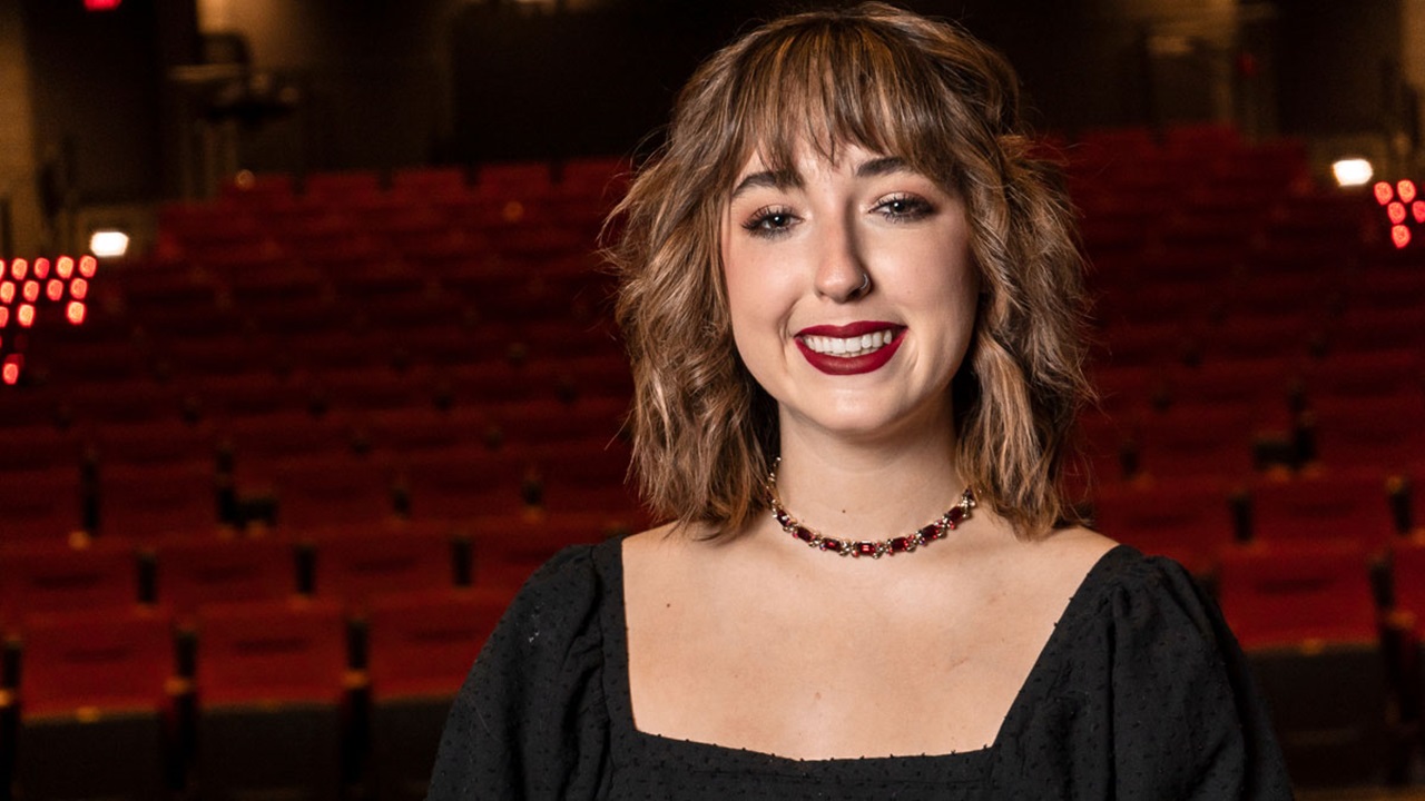 A close-up portrait of Kylie Groves smiling in a theater.