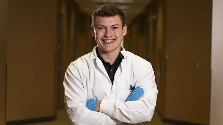 Benjamin VanBockern is smiling at the camera with his arms crossed. He is wearing a white coat.