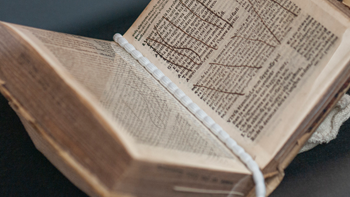 An open book with a white string down the middle of the pages and brown marks on the pages.