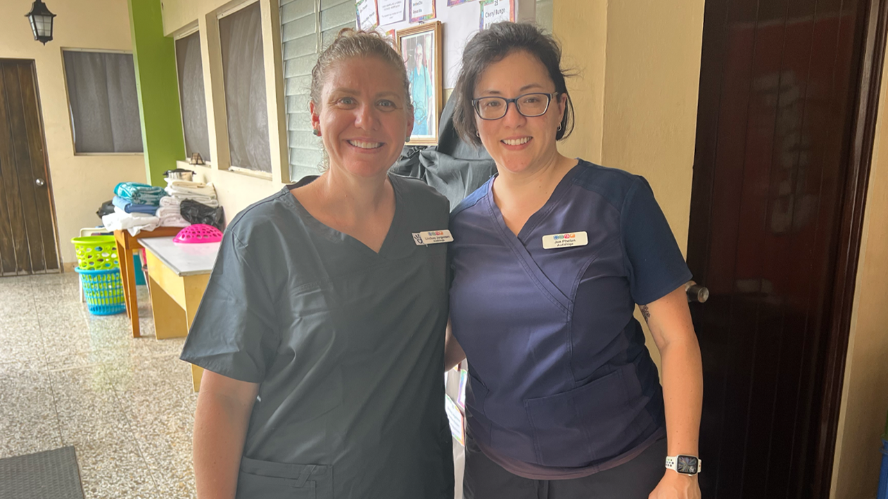 Lindsey Jorgensen and Jennifer Phelan stand together for a photo in their scrubs.