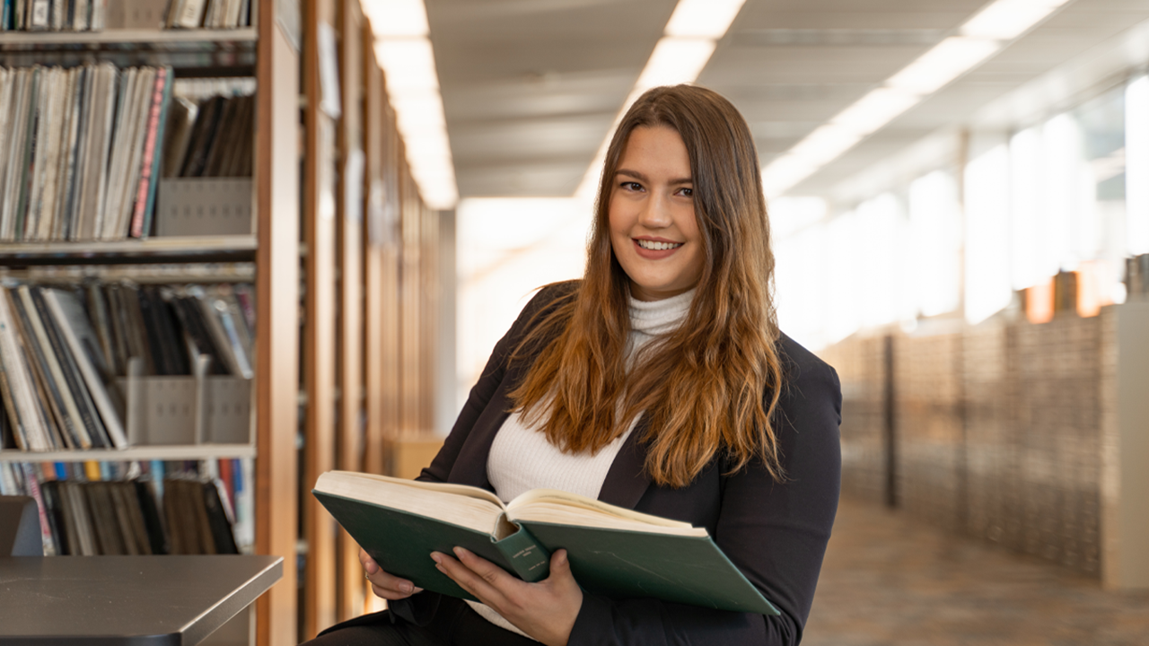 A photo of Mattie Jones flipping through a book in the library.