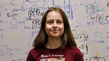 Oleksandra Lukine in front of a whiteboard with equations written on it.