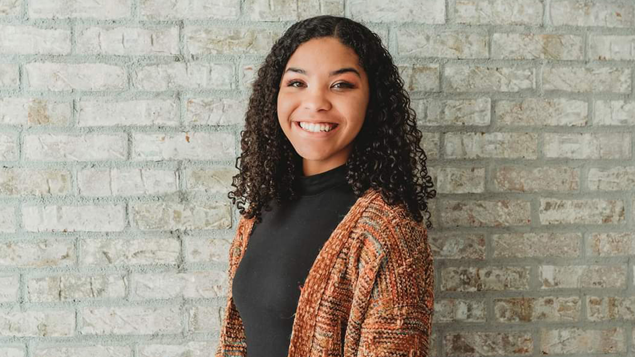 Student Standing in front of Brick Wall