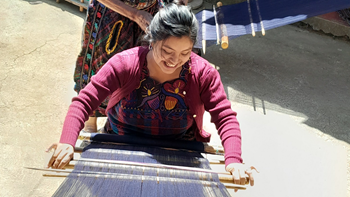 A person does a traditional Guatemalan backstrap weaving technique.