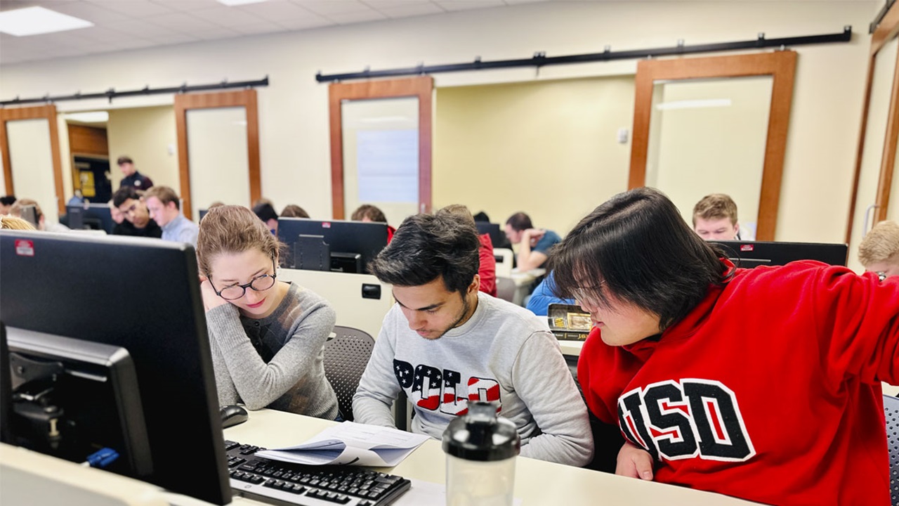 Three USD students work around a computer during the International Collegiate Programming Competition Three USD students work around a computer during the International Collegiate Programming Competition