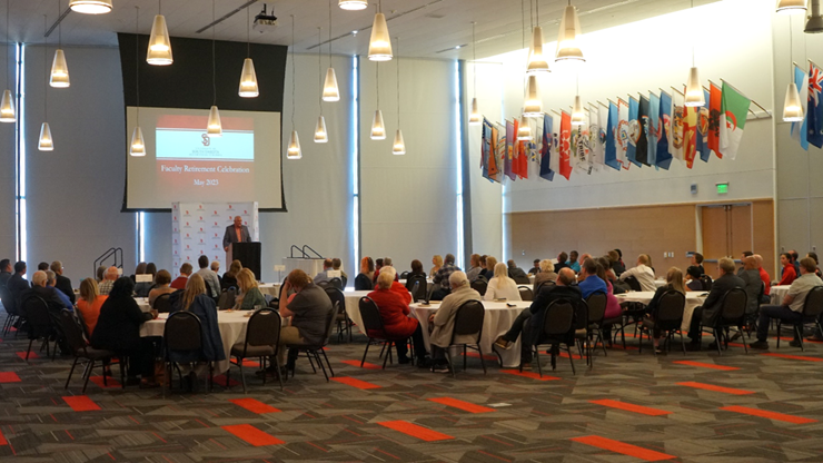 Mark Yockey stands at a podium and presents to tables full of individuals in the MUC Ballroom.