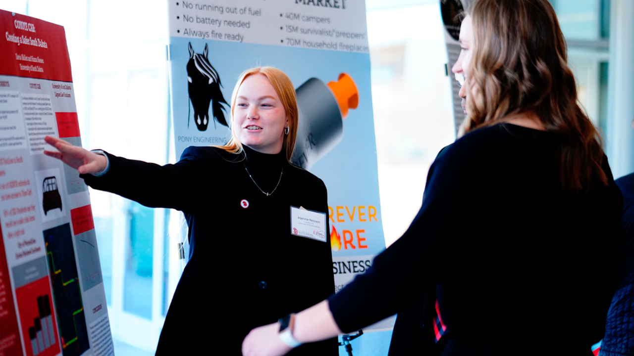 A student points at a poster board and presents.