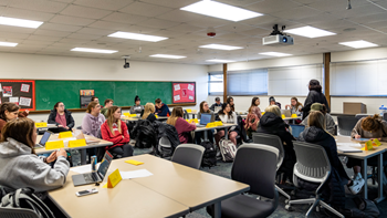 Students in a classroom listen to their professor lecture.