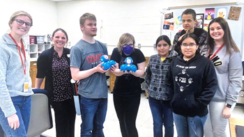 Students stand in a group and hold DASH robots. 