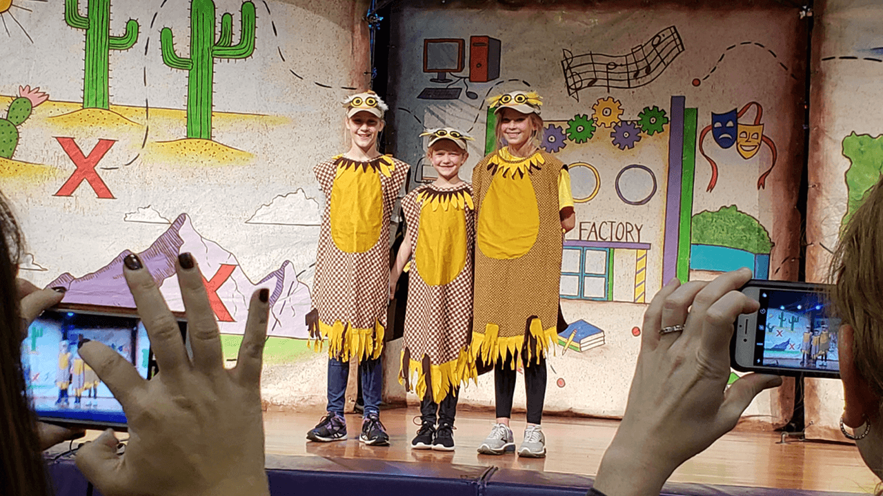 Children standing on stage in costumes