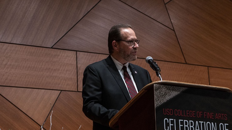 Bruce Kelley stands behind a lectern at the the 2022 Celebration of Excellence event. He is talking to the crowd.