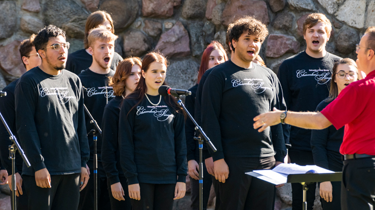 Students sing an an event outside.