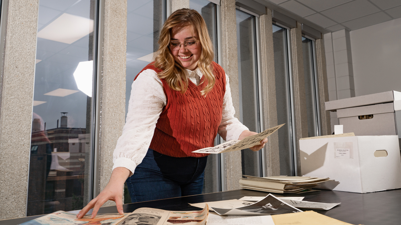 A photo of Veronica Knippling. She is looking down and sorting papers on a table.