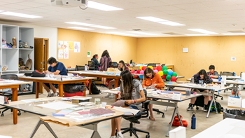 Students sit at desks in an art room and work on projects at the Oscar Howe Summer Art Institute.