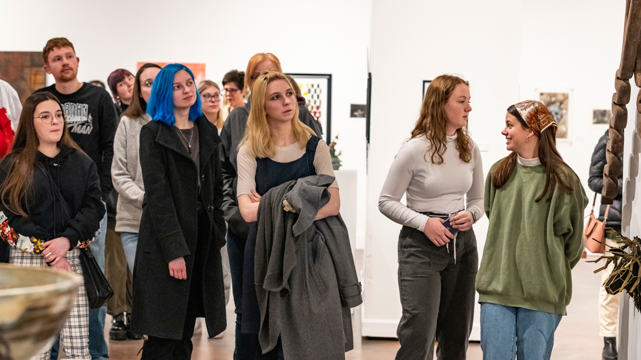People stand in an art gallery and look at art.